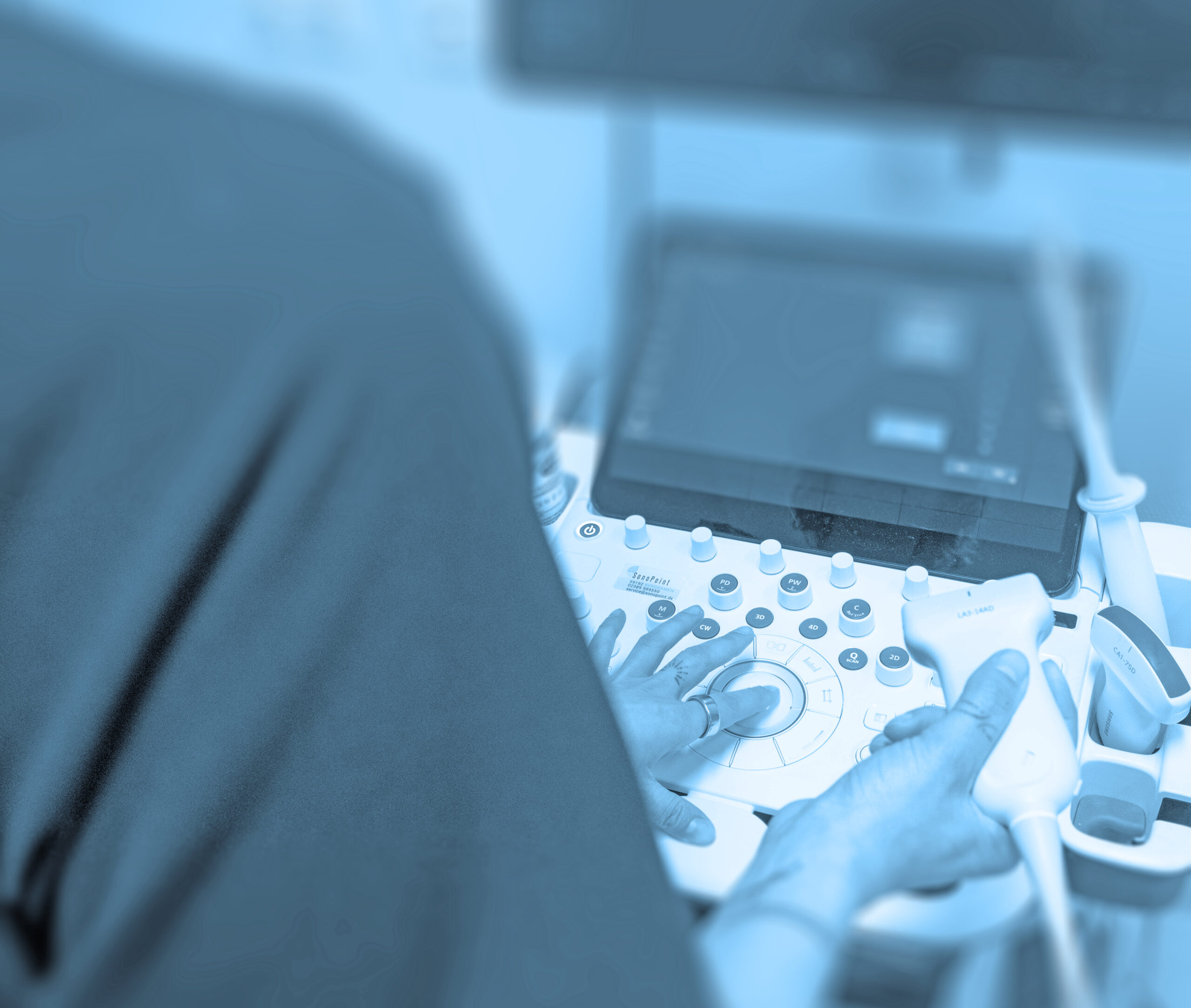Hände bedienen ein Ultraschallgerät während einer sonographischen Untersuchung